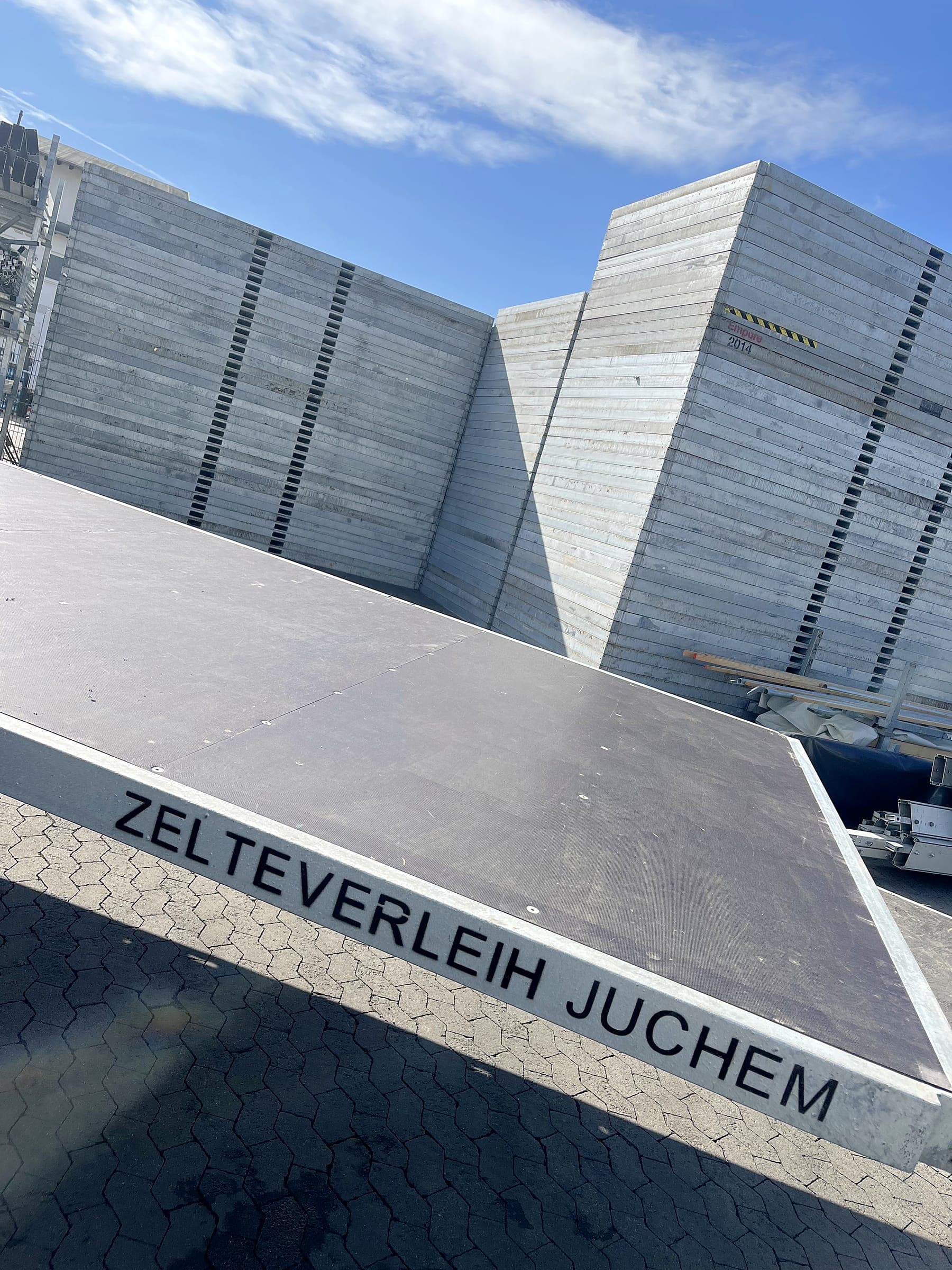 Gestapelte Schwerlastbodenelemente mit dem Schriftzug „Zeltverleih Juchem“ im Lager
